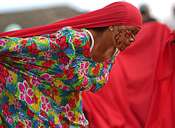Mujer wayuu con manta floral y tocado rojo participa en una ceremonia